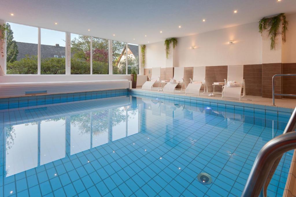 a large swimming pool with white chairs in a building at Hotel Haus Andrea in Winterberg