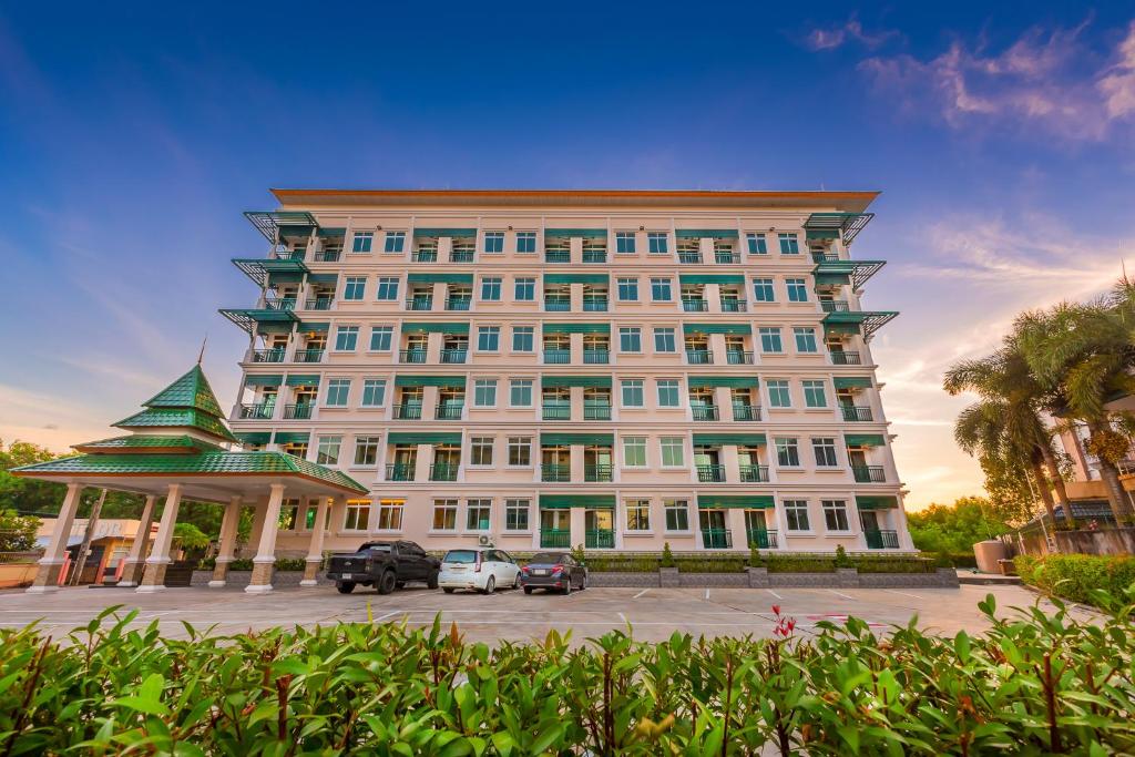 素叻Evergreen Suite Hotel的一座大型建筑,前面有汽车停放