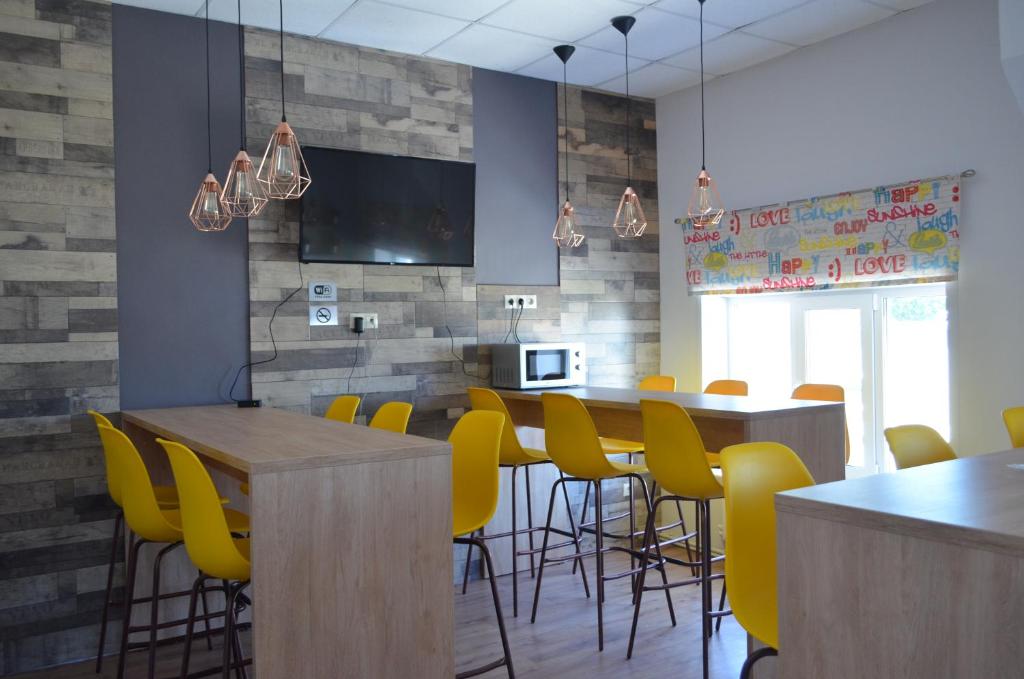 a restaurant with yellow chairs and tables and a tv at Hostel Energia in Kazan