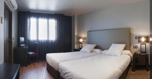 a hotel room with two beds and a window at Hotel Valcarce León in Onzonilla