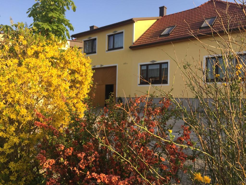 a yellow house with trees and flowers in front of it at Amstetter’s Ferienwohnung in Waldenstein