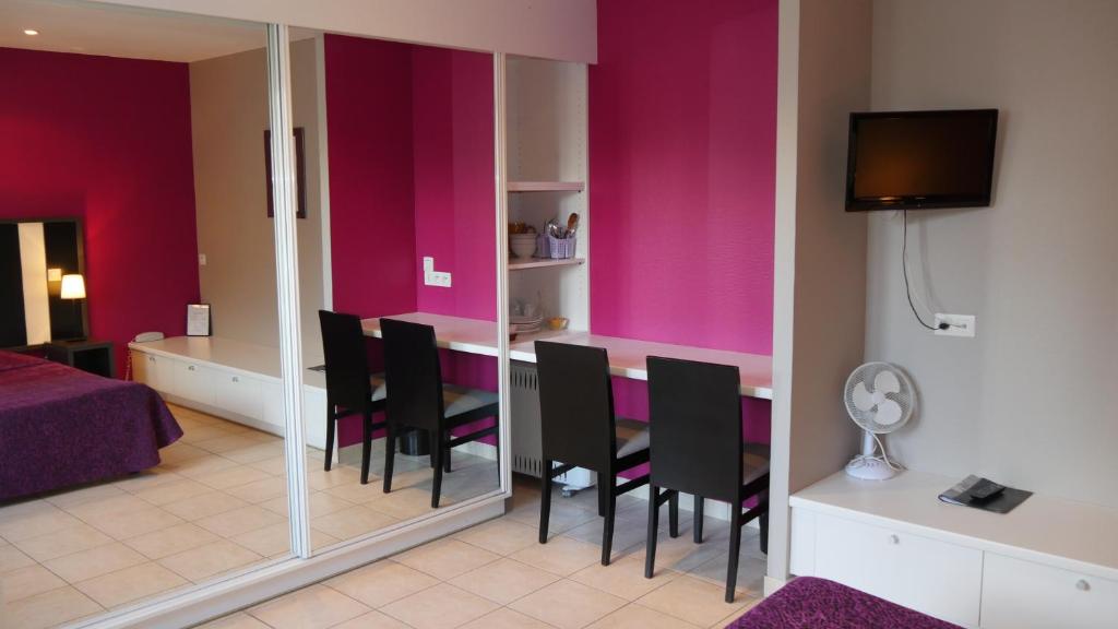 une salle à manger avec des murs roses et une table avec des chaises dans l'établissement Hôtel Savary, à La Rochelle