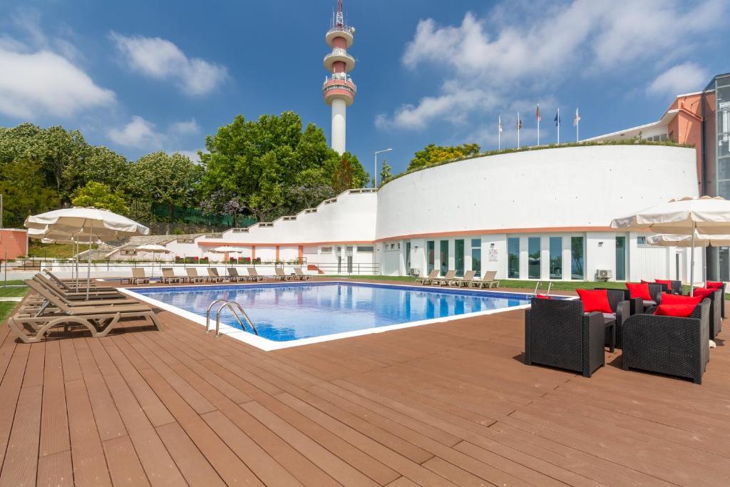 a swimming pool with chairs and a building with a tower at Luna Hotel Turismo in Abrantes