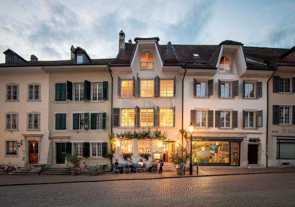 um grande edifício branco com pessoas sentadas fora dele em Baseltor Hotel & Restaurant em Solothurn