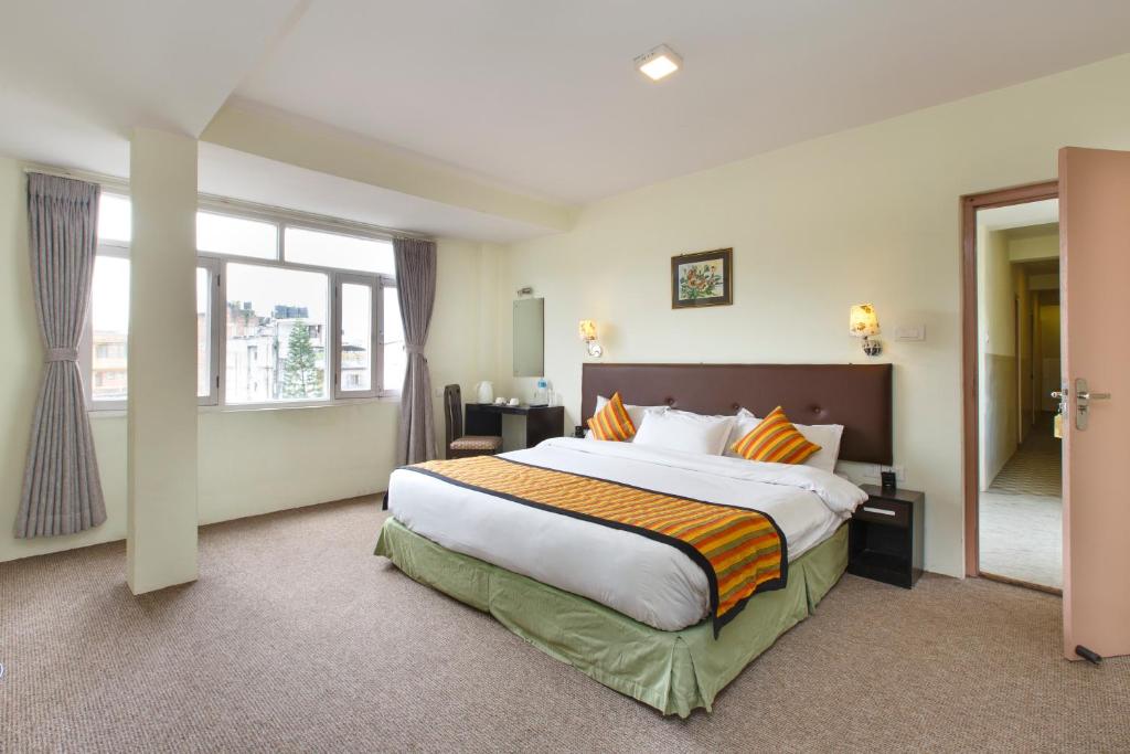 een slaapkamer met een groot bed en een groot raam bij Hotel Serenity in Kathmandu
