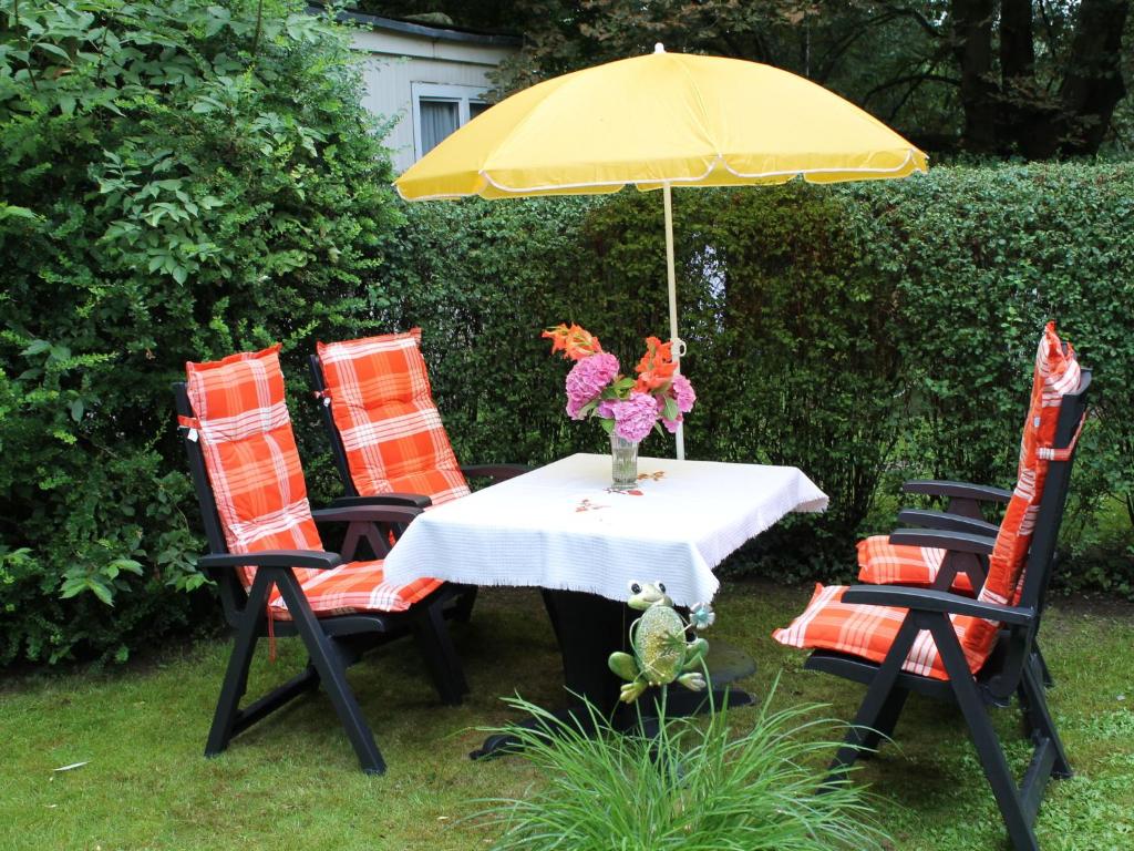 a table with a yellow umbrella and four chairs at Charming Apartment in Kr pelin with Barbecue in Kröpelin