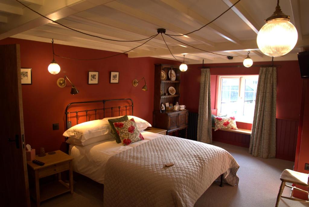 een slaapkamer met een bed in een kamer met rode muren bij Bridge House in Bampton