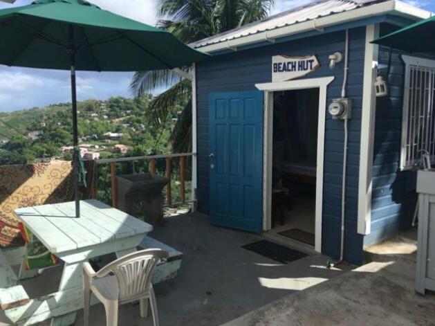 une maison bleue avec une table et un parasol dans l'établissement Cosy Hut, à Saint-Georges