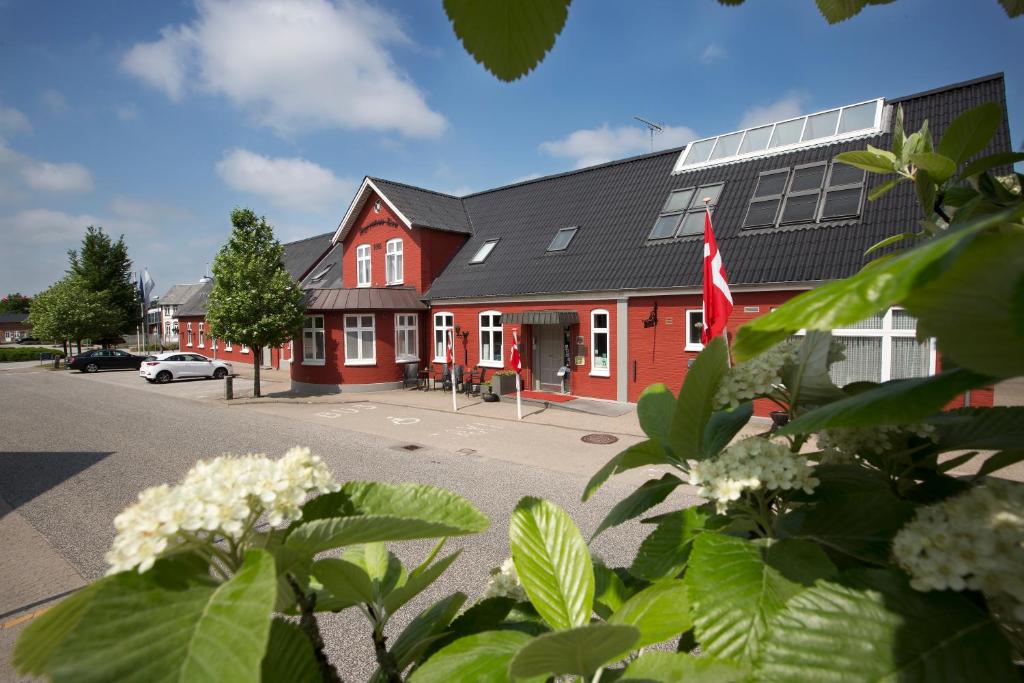 a red building with a flag in a parking lot at Agerskov Kro & Hotel in Agerskov