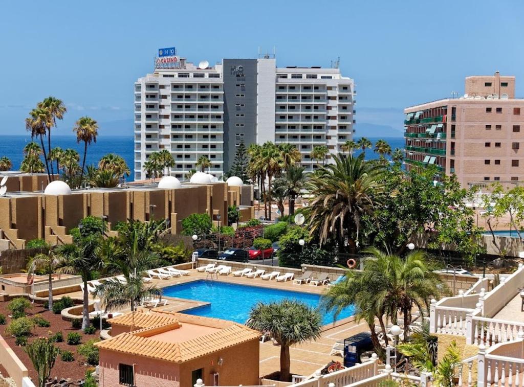 a resort with a pool and palm trees and buildings at Studioapartment Borinquen in Playa Fañabe