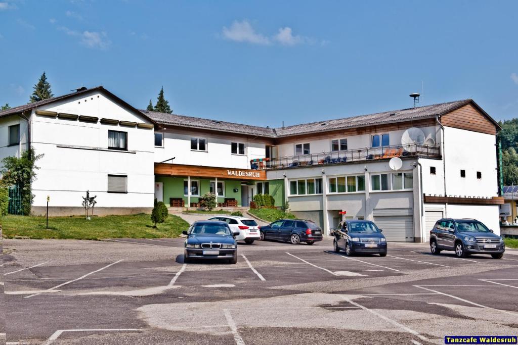 a large white building with cars parked in a parking lot at Pension Waldesruh in Linz