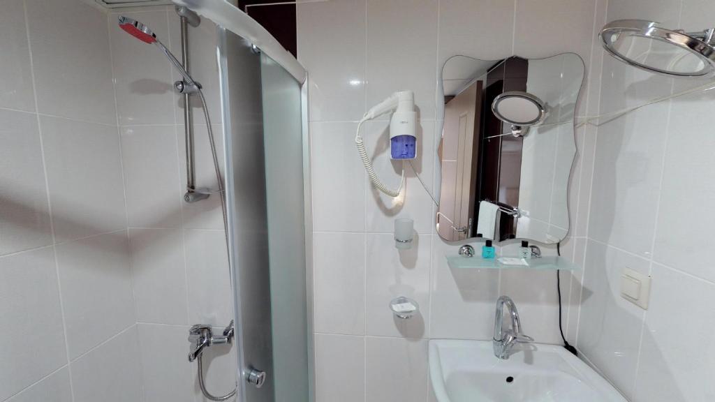 a bathroom with a shower and a sink and a mirror at Patron Hotel in Antalya