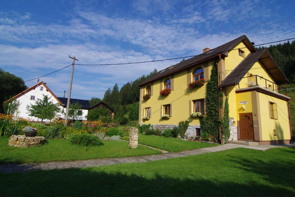 a yellow house with flowers in a yard at Penzion Gott in Lipova Lazne
