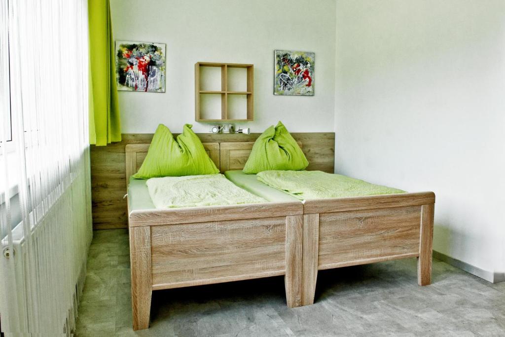 uma cama de madeira com almofadas verdes num quarto em Pension Waldesruh em Linz