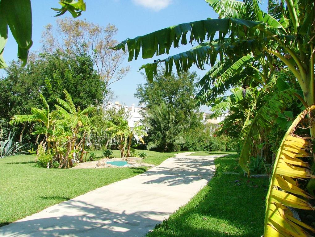 a path through a park with trees and grass at El Cortijo de Zahara by QHotels in Zahara de los Atunes