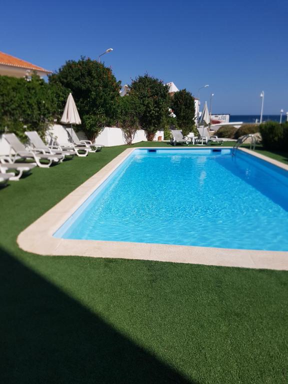 a large swimming pool with lawn chairs and chairs at Casa Praia Mar in Salema
