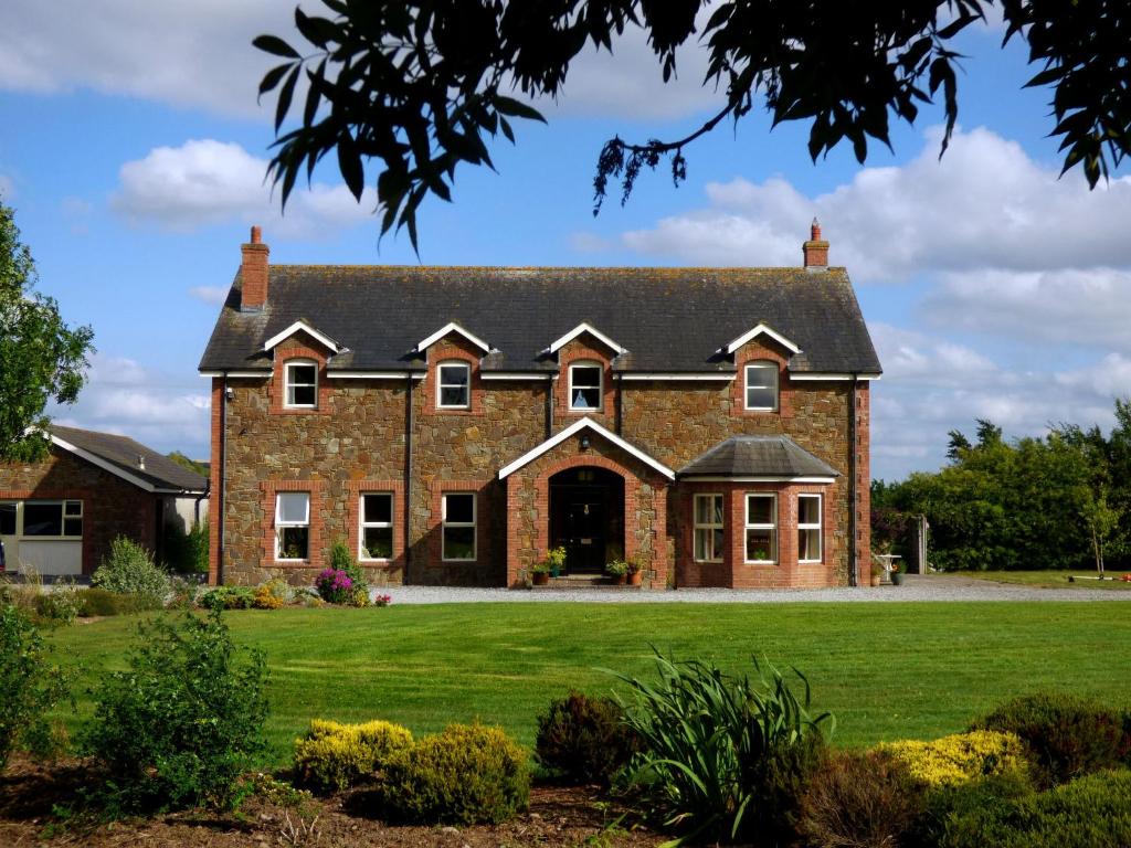 uma grande casa de tijolos com um relvado verde em Ash House Bed and Breakfast em Calverstown