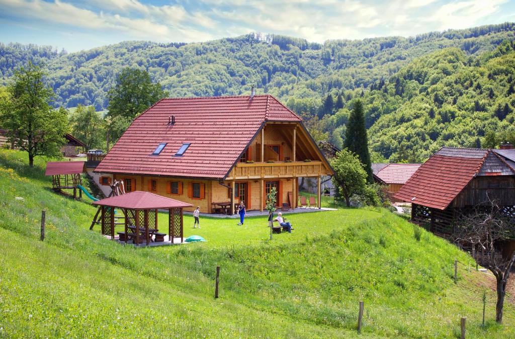 une grande maison en bois sur une colline dans un champ dans l'établissement Farm Stay Pirc, à Laško