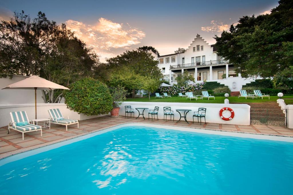 a swimming pool with chairs and a hotel in the background at The Cellars-Hohenort in Cape Town
