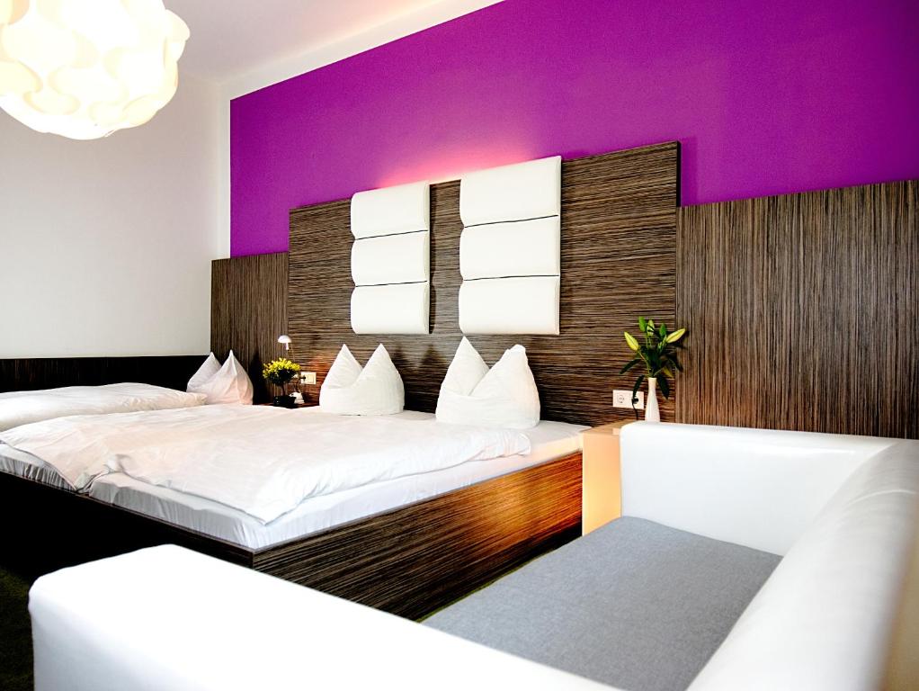 2 łóżka w pokoju z fioletową ścianą w obiekcie Hotel Albrechtshof Gohrisch w mieście Kurort Gohrisch