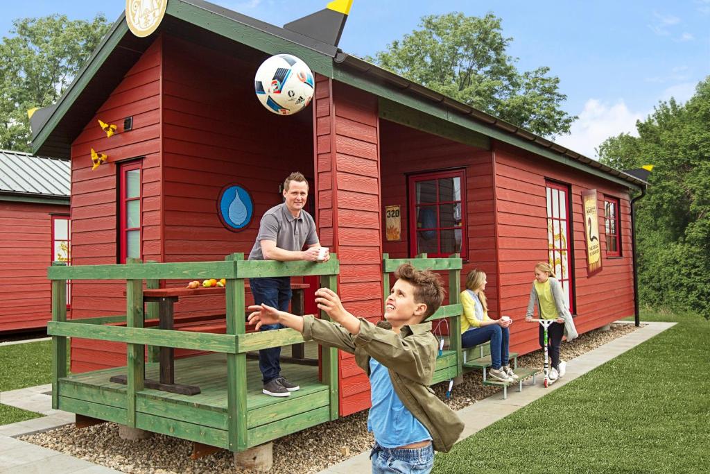 un hombre y un niño jugando con una pelota de fútbol en una casa de juego en LEGOLAND NINJAGO Cabins en Billund