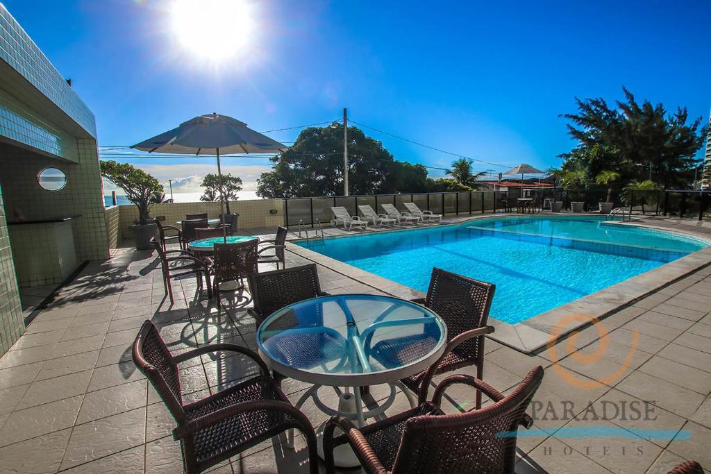 um pátio com uma mesa e cadeiras ao lado de uma piscina em Paradise Flat em Natal