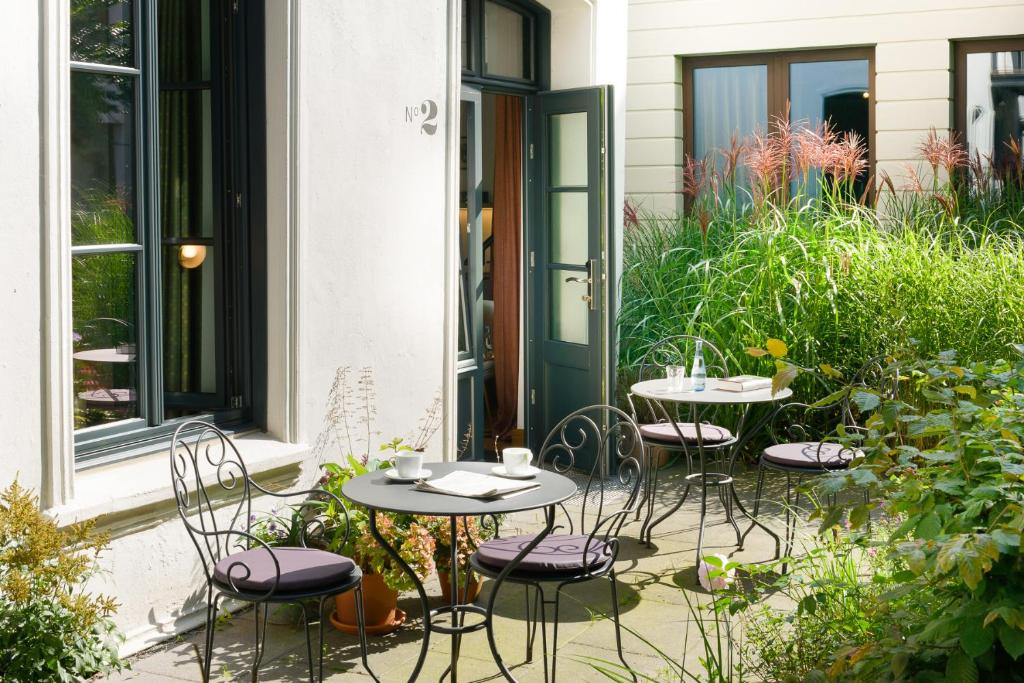 a patio with two tables and chairs in a garden at Das kleine Grindel in Hamburg