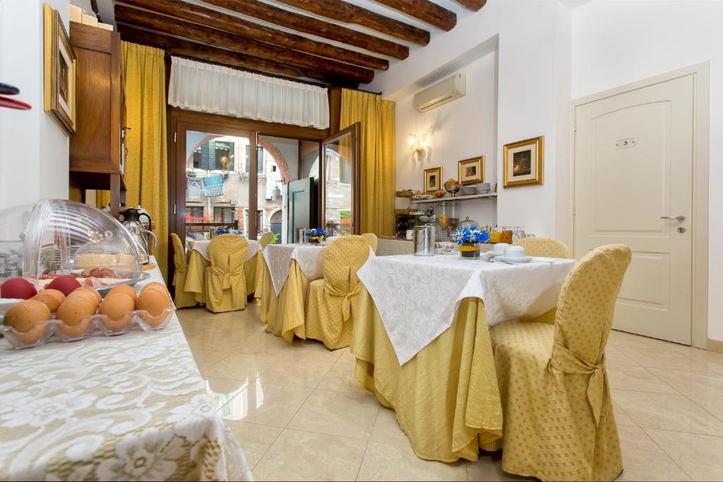 a dining room with two tables with yellow clothed chairs at Alla Vite Dorata in Venice