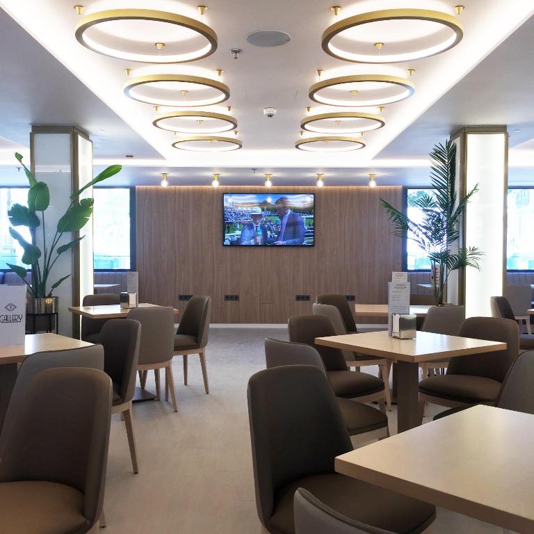 poczekalnia ze stołami i krzesłami oraz telewizorem z płaskim ekranem w obiekcie Hotel Presidente 4 sup w mieście Benidorm