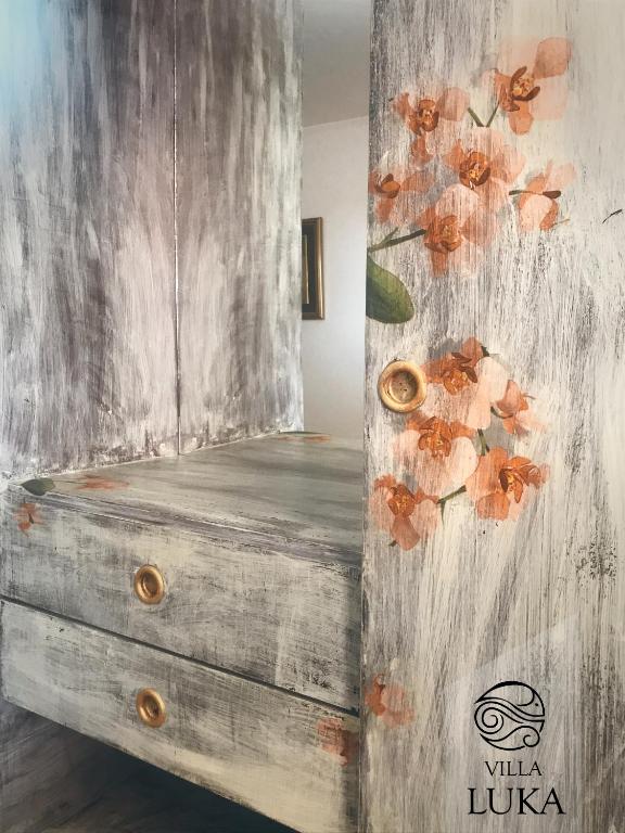a wooden dresser with a painting of flowers on it at Apartments Villa Luka in Sveti Stefan