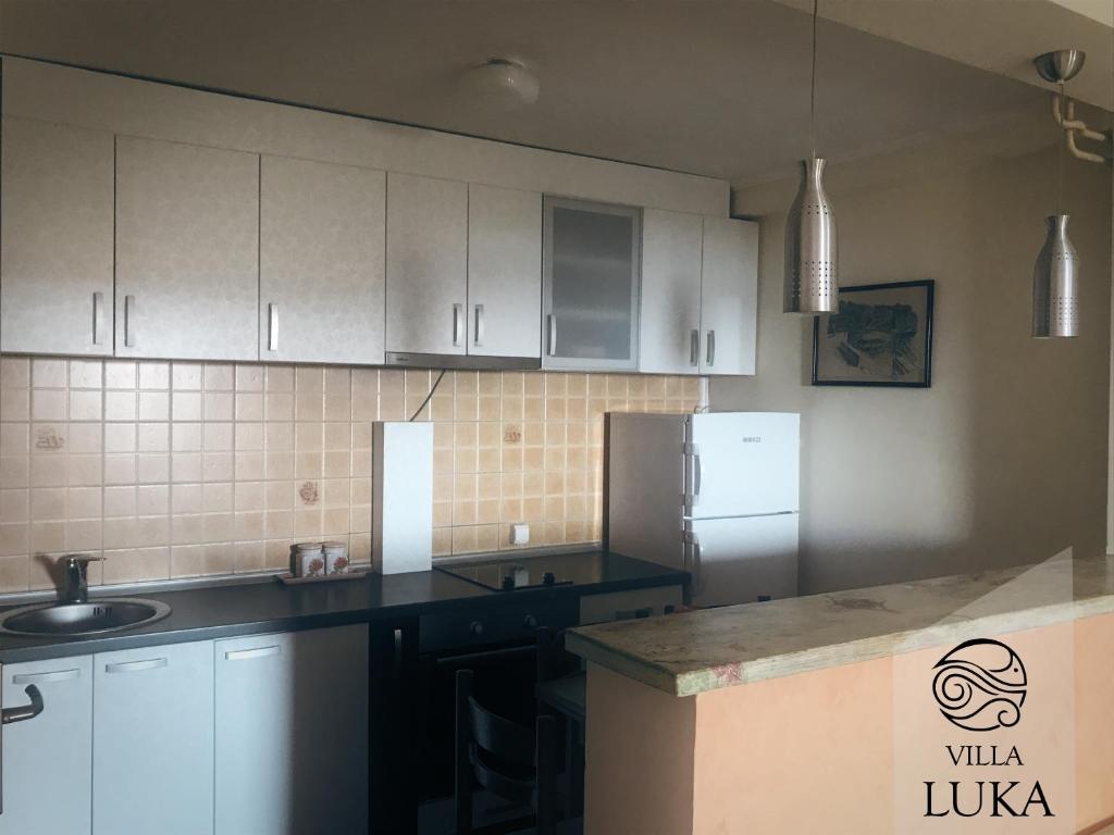 a kitchen with white cabinets and a refrigerator at Apartments Villa Luka in Sveti Stefan