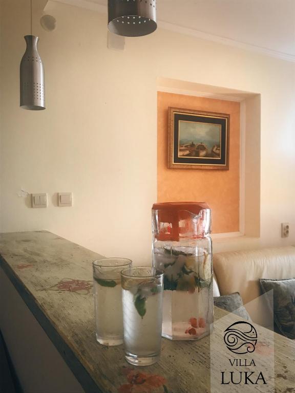 a table with three glasses and a vase on it at Apartments Villa Luka in Sveti Stefan
