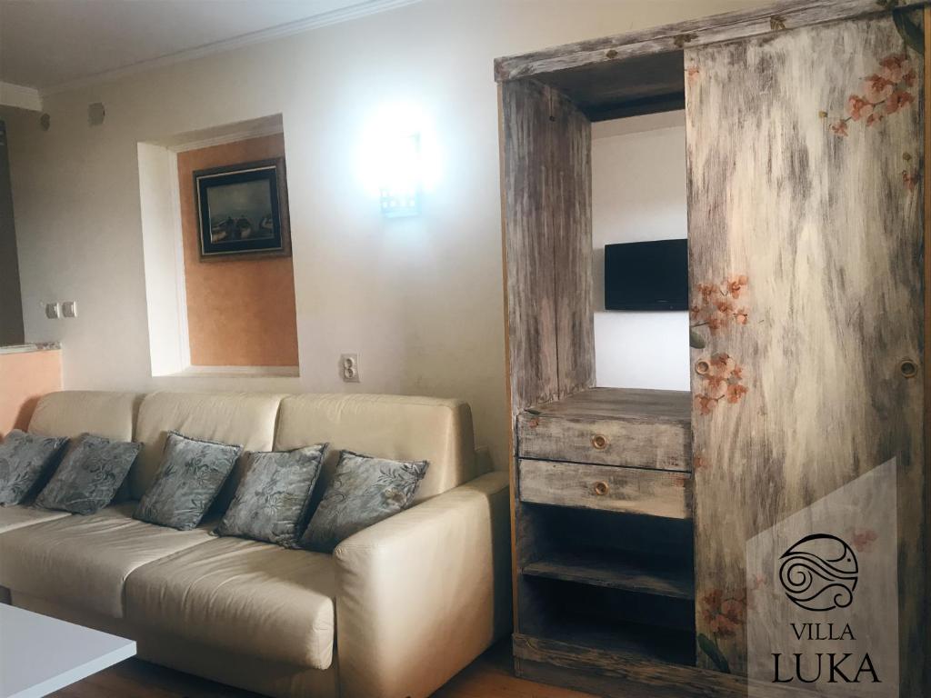 a living room with a couch and a wooden door at Apartments Villa Luka in Sveti Stefan
