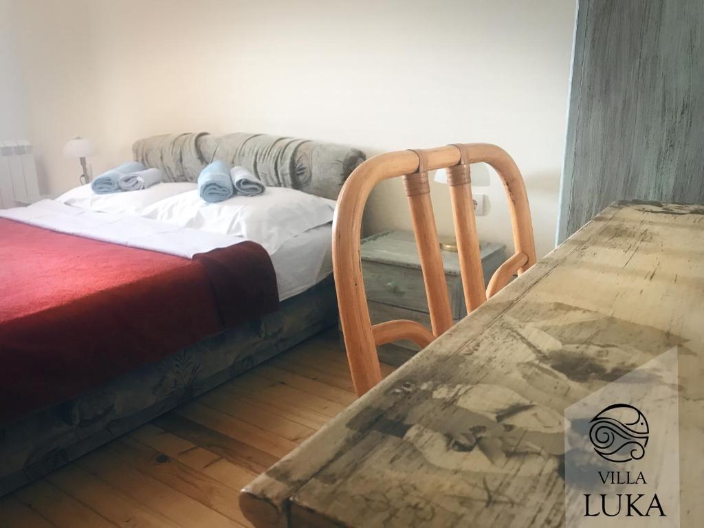 a bedroom with a bed and a chair and a table at Apartments Villa Luka in Sveti Stefan