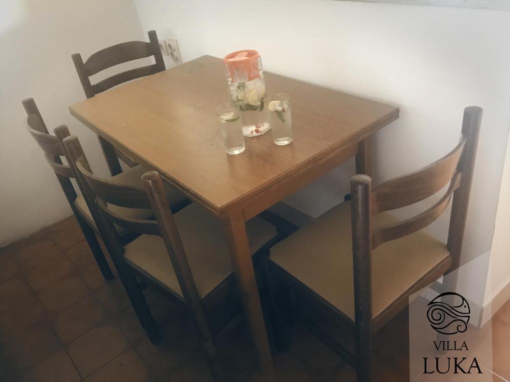 a wooden table with chairs and glasses on it at Apartments Villa Luka in Sveti Stefan