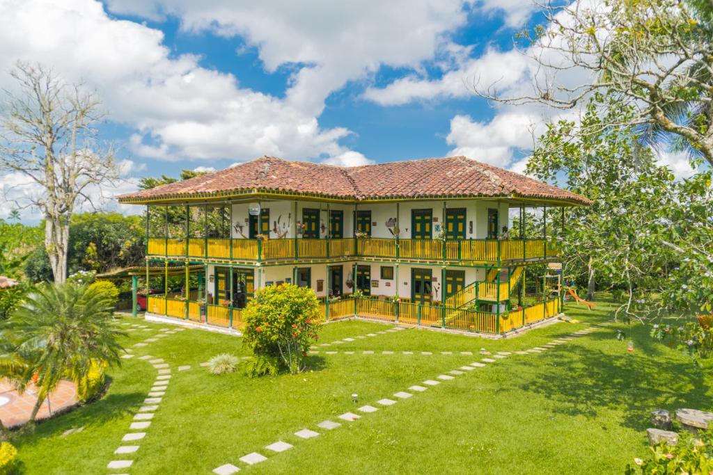 une grande maison jaune avec une aire de jeux dans la cour dans l'établissement Finca Hotel el Palmar, à Montenegro