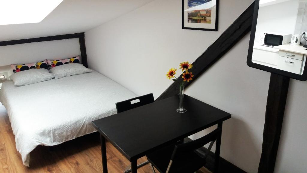 a bedroom with a bed and a table with flowers on it at Nice Attic Studio Close to Old Town Air Conditioning - Klimatyzacja in Krakow