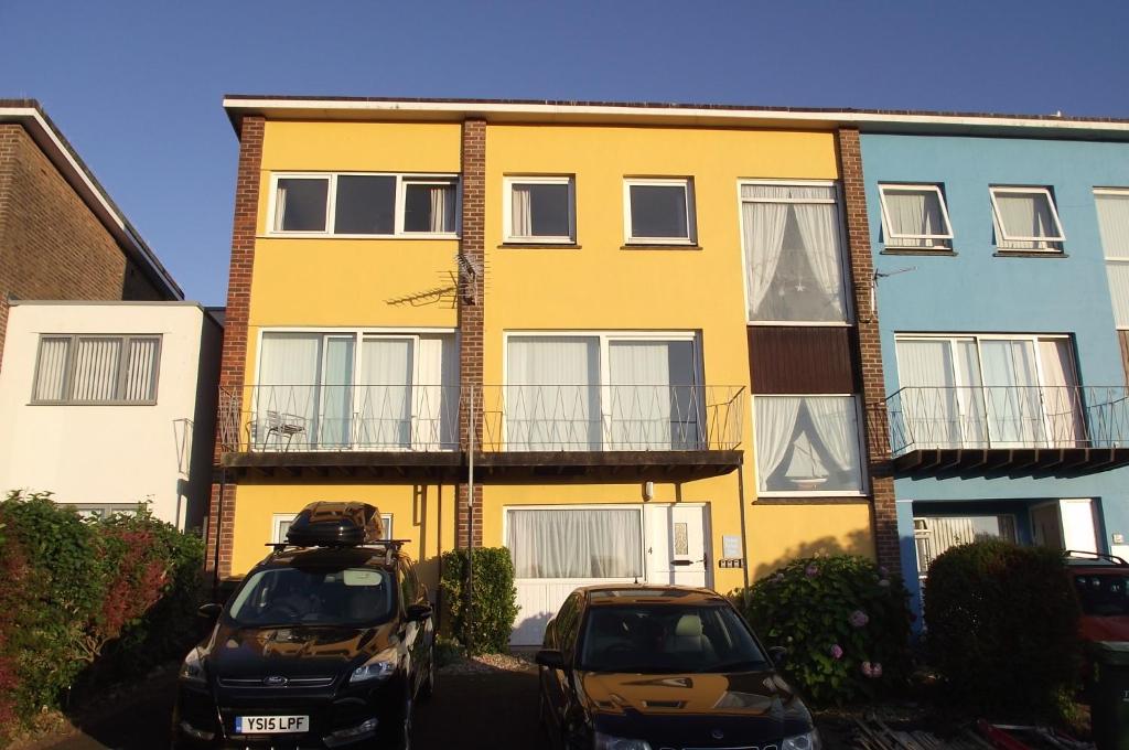 two cars parked in front of a yellow building at Sea Crest in Brixham