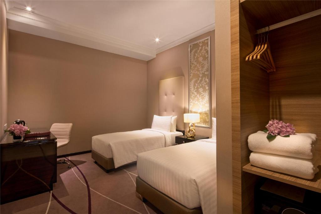 A twin room with two single beds, a television console and open wardrobe.