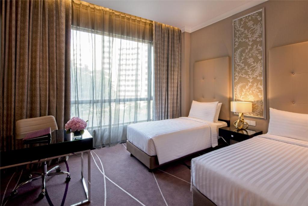 A twin room places two single beds beside a bright window and a compact desk.