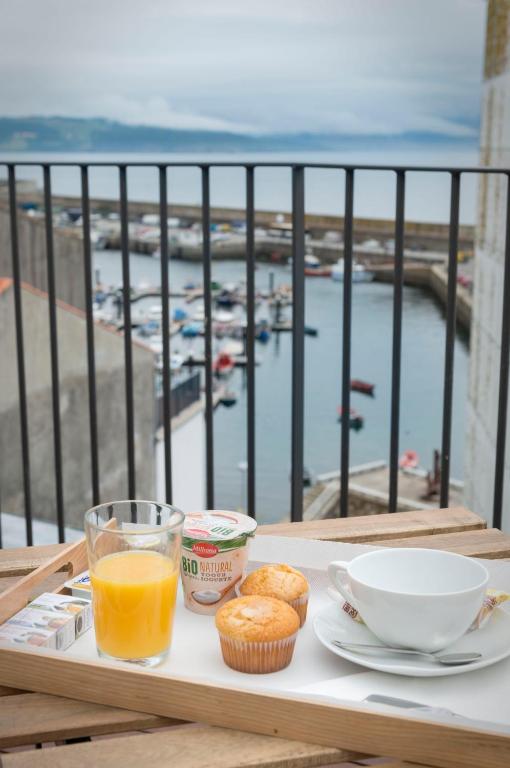 bandeja con un desayuno de zumo de naranja y magdalenas en el balcón en Hotel SempreFisterra, en Finisterre