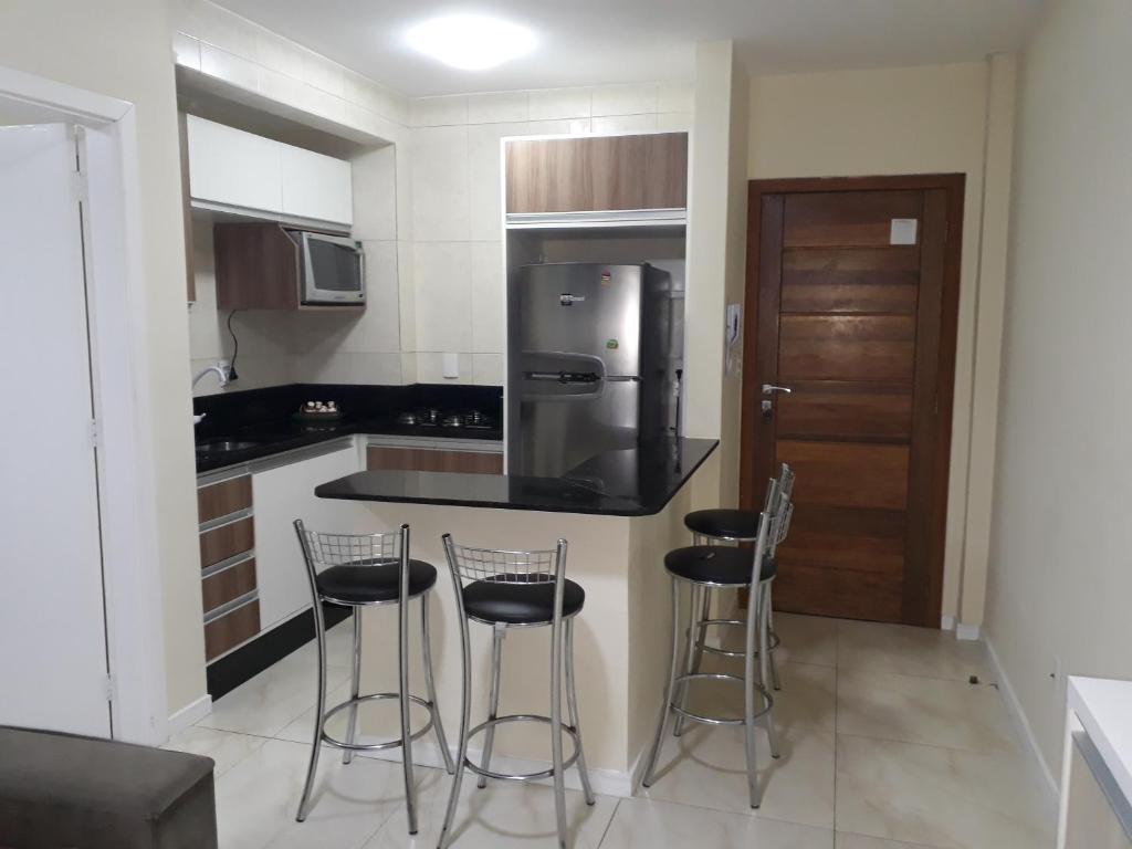 a kitchen with three bar stools and a refrigerator at Ótimo Apto. 180 metros da Praia in Balneário Camboriú