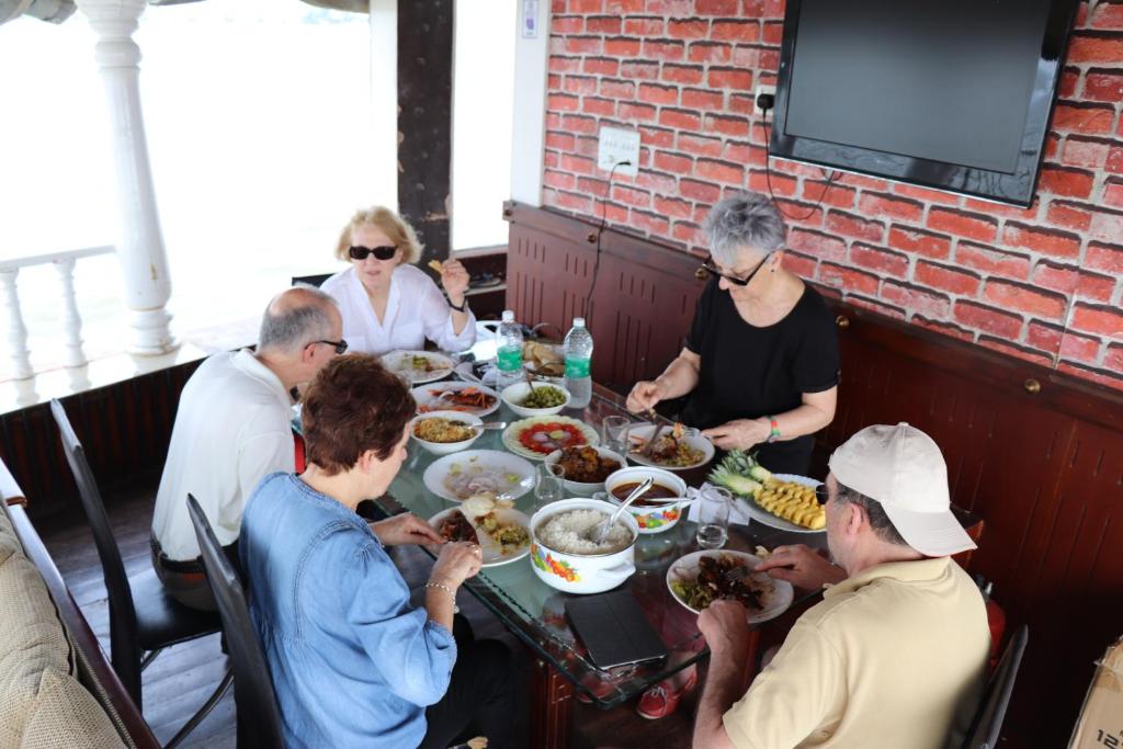 Eine Gruppe von Menschen, die an einem Tisch sitzen und Essen essen. in der Unterkunft Marari houseboat VACCINATED STAFF in Mararikulam