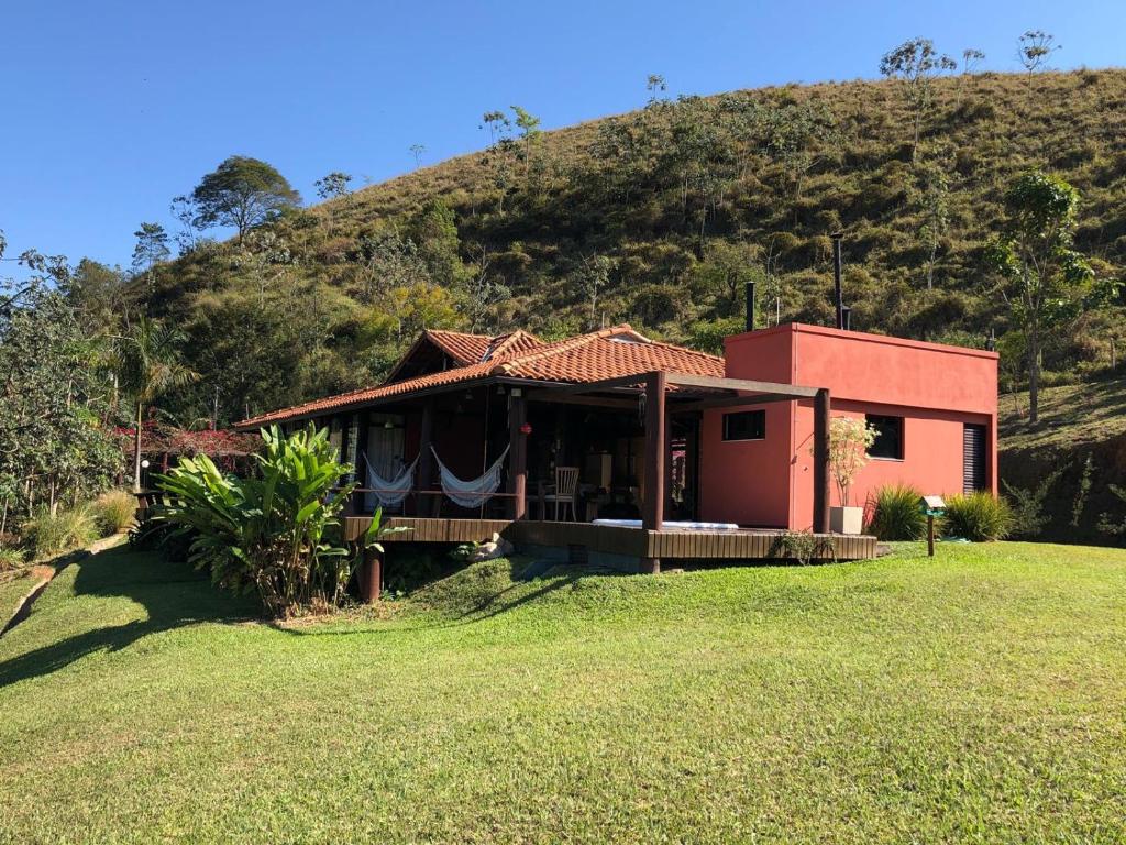 una pequeña casa roja frente a una colina en Linda casa de frente para a Bocaina en São José do Barreiro