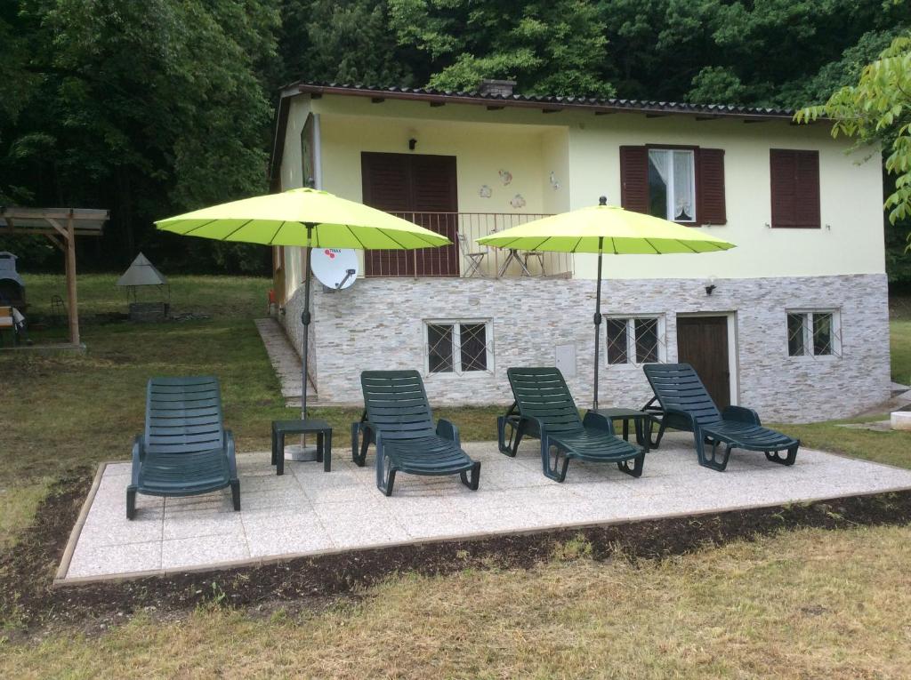 a group of chairs and umbrellas in front of a house at Haus Judith in Steindorf am Ossiacher See