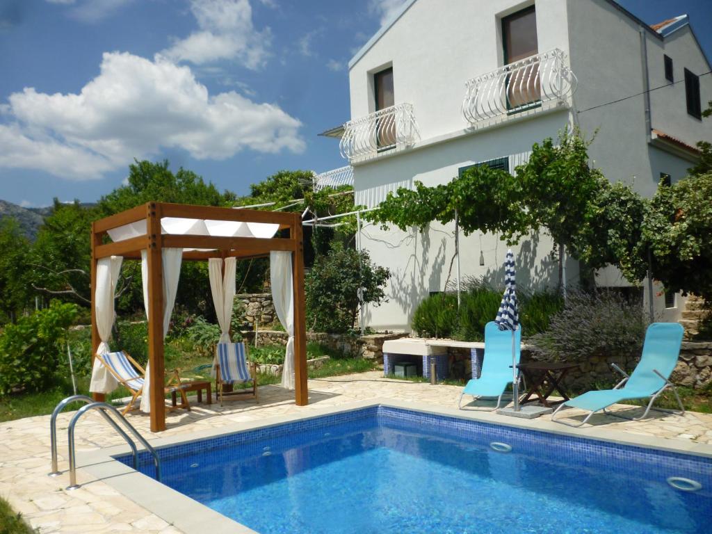 een zwembad met stoelen, een prieel en een huis bij Apartment Panorama in Klis