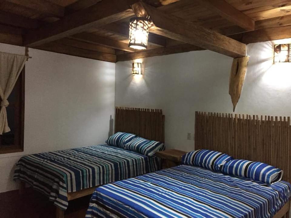 two beds in a room with wooden ceilings at Cabañas La Isla Chacahua in Guayabas