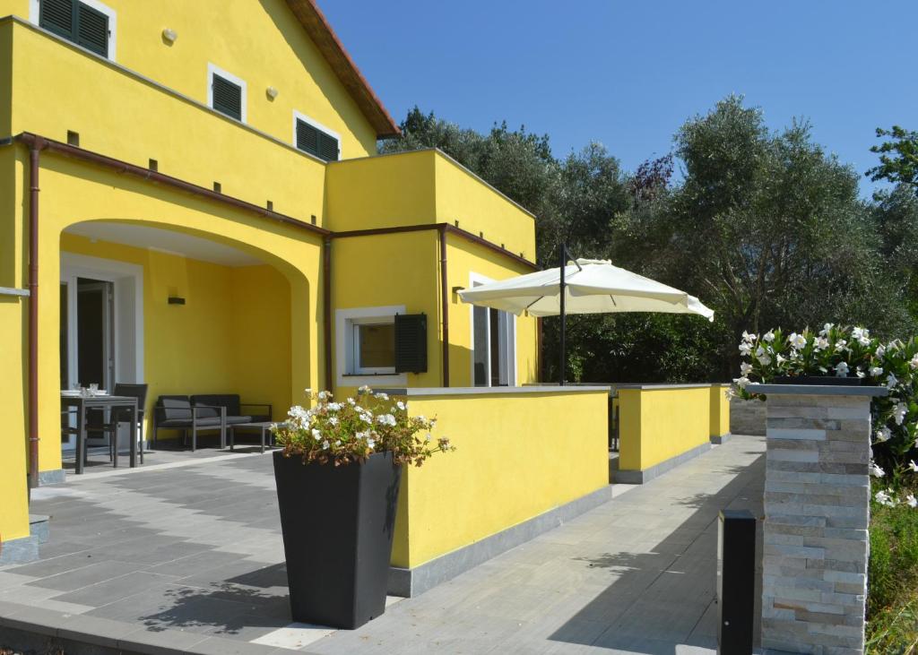 una casa gialla con ombrellone e patio di A Casa Mia a Levanto