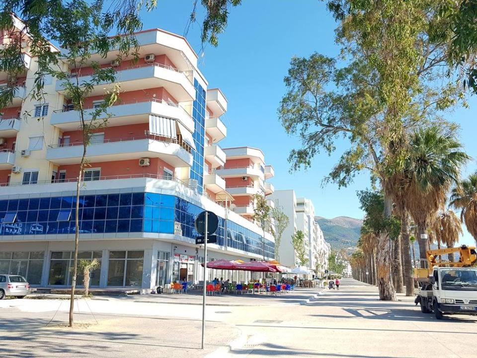 a large building on a city street with palm trees at Cold Water Residence in Vlorë