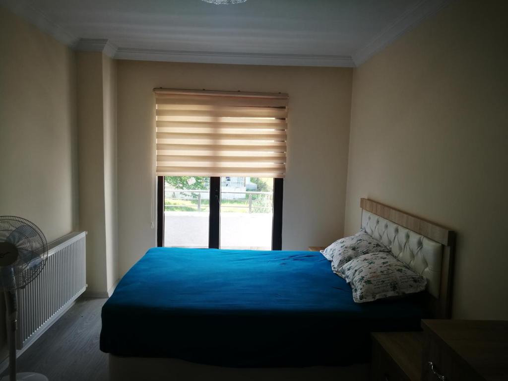 Un dormitorio con una cama azul y una ventana en جوهرة جينارجيك, en Çınarcık